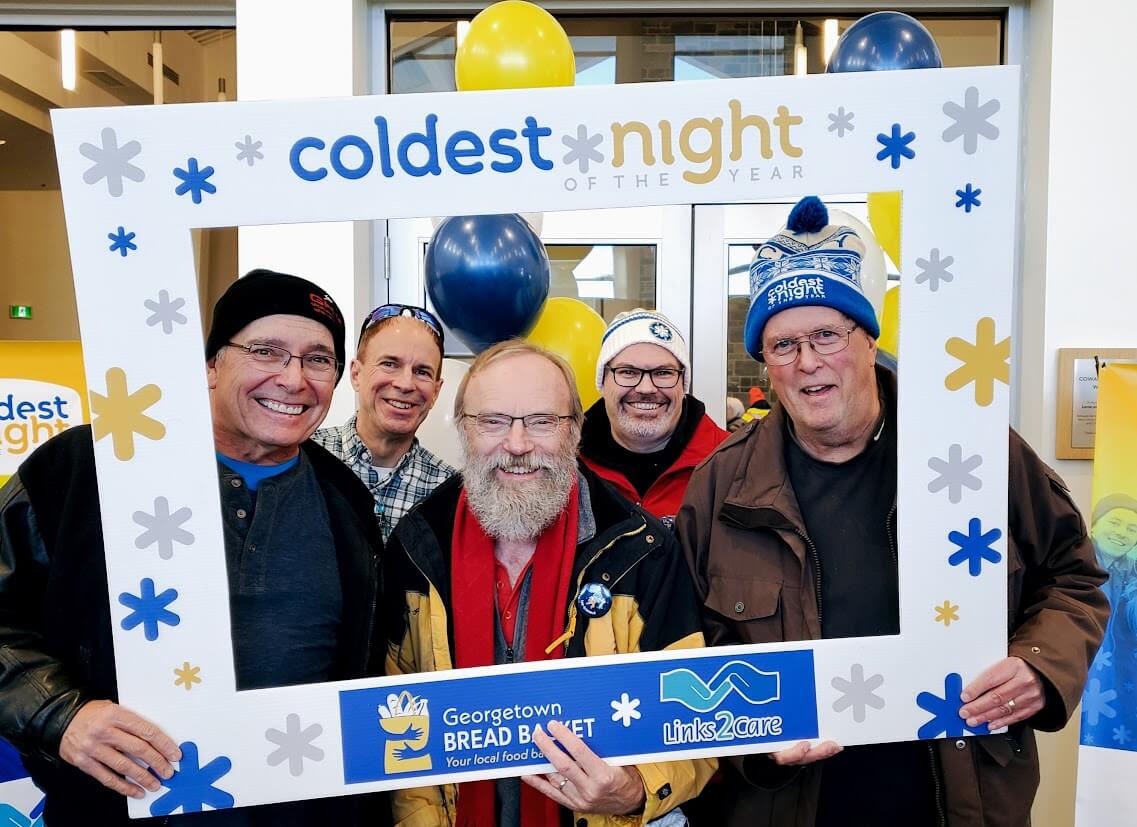 Five gentlemen smiling at the camera and the three in the front are holding a frame that says coldest night of the year