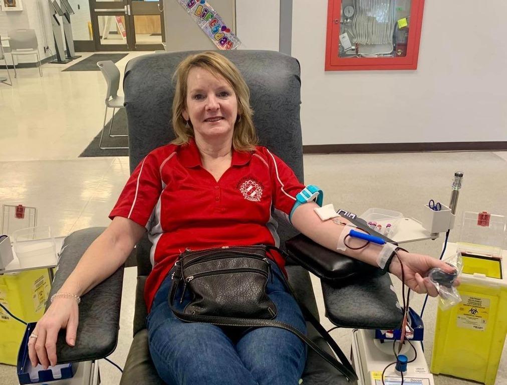 A woman donating blood in Kin Canada polo shirt